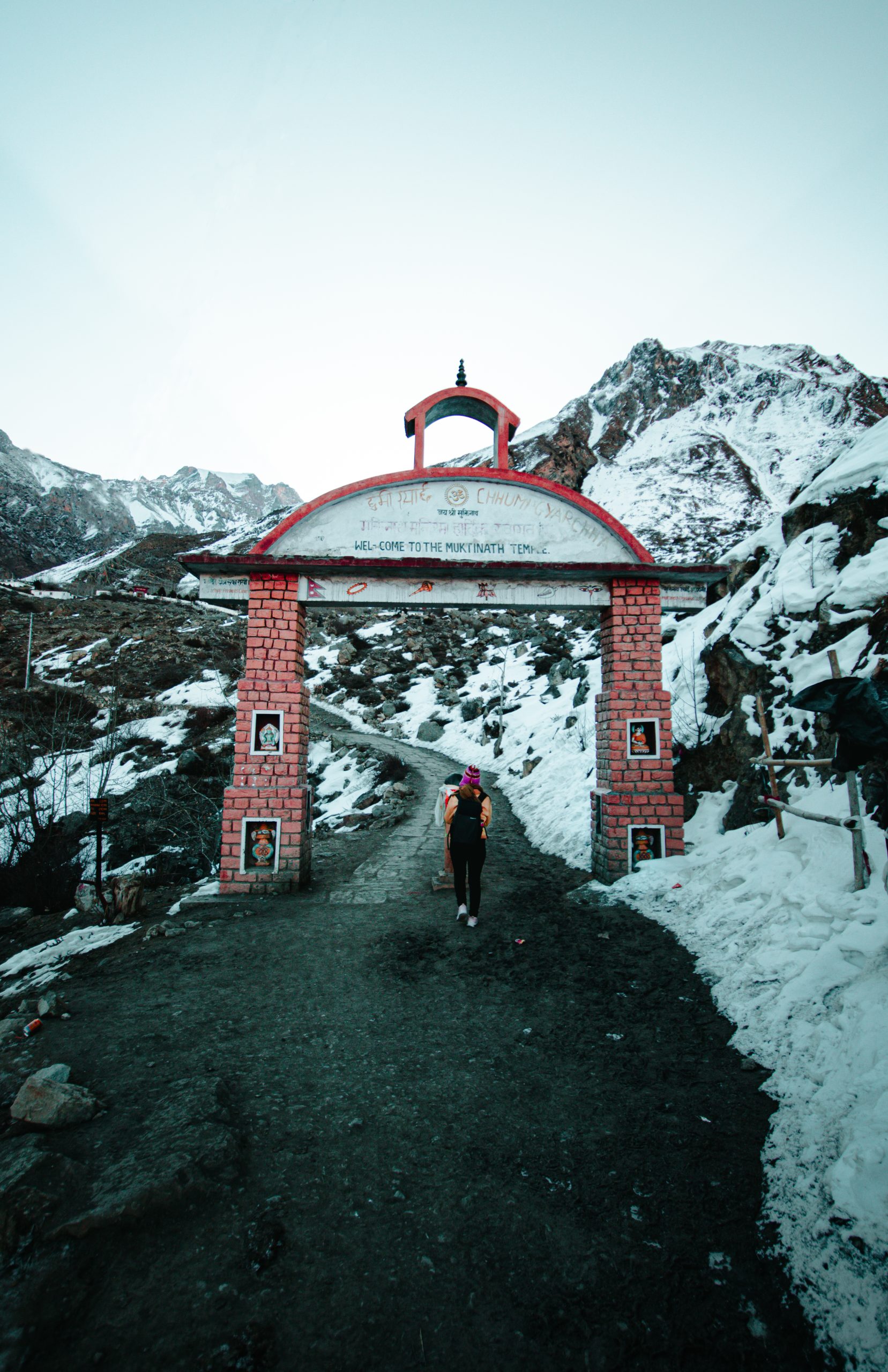 Unrecognizable woman walking through brick gate in mountainous terrain